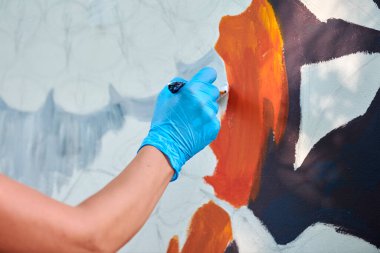 Kadın ressam eli boya fırçasını tutuyor ve açık hava resim festivalinde beyaz tuval üzerine soyut gerçeküstü resimler çiziyor, resim resim süreci. Kadın sanatçı atmosferik gerçeküstü resim çiziyor.