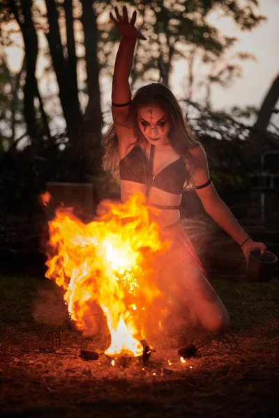 Girl fire dancing performance at outdoor art festival, smooth movements of female artist dancing igniting flame of fire. Woman dancing with fire art performance, twilight forest background