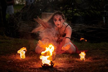 Açık hava sanat festivalinde kız ateş dansı gösterisi, akvaryumlu kadın ateş gösterisi sanatçılarının düzgün hareketleri. Alevli dans eden kadın sanat performansı, alacakaranlık ormanı arka planı