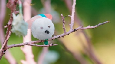 Pembe ağaç dalındaki yapay kuş anaokulunda el işi yapıyor. Şirin çocuklar pamuktan kuş zanaatı, simli taş ve ayçiçeği tohumu, gelişmekte olan çocuklar için açık hava dersleri