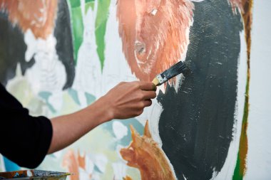 Ressam el fırçasını tutuyor ve açık hava resim festivalinde beyaz tuval üzerine soyut gerçeküstü görüntüler çiziyor, resim resim süreci. Sanatçı atmosferik resim çizer