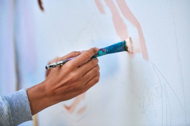 Ressam el fırçasını tutuyor ve açık hava resim festivalinde beyaz tuval üzerine soyut gerçeküstü görüntüler çiziyor, resim resim süreci. Sanatçı atmosferik resim çizer