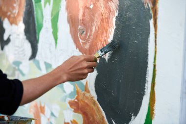 Ressam el fırçasını tutuyor ve açık hava resim festivalinde beyaz tuval üzerine soyut gerçeküstü görüntüler çiziyor, resim resim süreci. Sanatçı atmosferik resim çizer