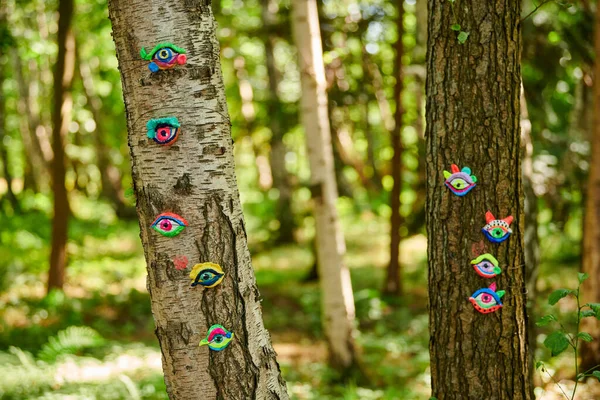 Art object of human eyes on tree trunk in green forest background, trees sight feeling ecological concept, environmental protection outdoor art exhibition. Trees sense of vision, unity with nature