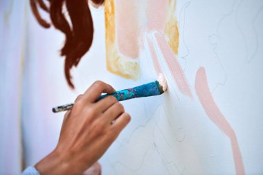 Ressam el fırçasını tutuyor ve açık hava resim festivalinde beyaz tuval üzerine soyut gerçeküstü görüntüler çiziyor, resim resim süreci. Sanatçı atmosferik resim çizer