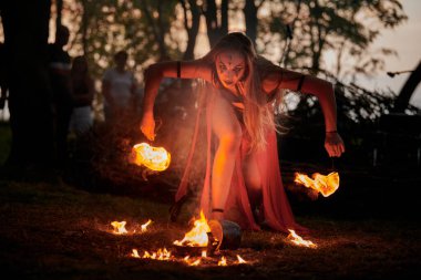 Açık hava sanat festivalinde kız ateş dansı gösterisi, meşaleli kadın ateş gösterisi sanatçısının düzgün hareketleri. Alevli dans eden kadın sanat performansı, alacakaranlık ormanı arka planı
