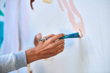 Ressam el fırçasını tutuyor ve açık hava resim festivalinde beyaz tuval üzerine soyut gerçeküstü görüntüler çiziyor, resim resim süreci. Sanatçı atmosferik resim çizer