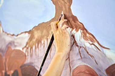 Ressam kız elinde boya fırçası ve açık hava resim festivalinde beyaz tuval üzerine soyut gerçeküstü manzara çiziyor, resim resim süreci. Kadın sanatçı atmosferik gerçeküstü resim çiziyor.