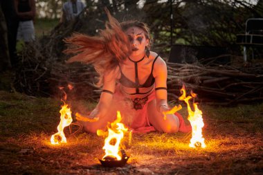 Açık hava sanat festivalinde kız ateş dansı gösterisi, akvaryumlu kadın ateş gösterisi sanatçılarının düzgün hareketleri. Alevli dans eden kadın sanat performansı, alacakaranlık ormanı arka planı