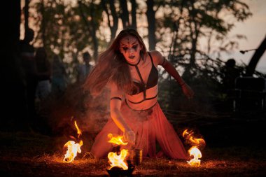 Açık hava sanat festivalinde kız ateş dansı gösterisi, akvaryumlu kadın ateş gösterisi sanatçılarının düzgün hareketleri. Alevli dans eden kadın sanat performansı, alacakaranlık ormanı arka planı