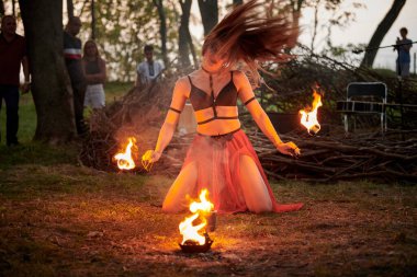 Açık hava sanat festivalinde kız ateş dansı gösterisi, meşaleli kadın ateş gösterisi sanatçısının düzgün hareketleri. Alevli dans eden kadın sanat performansı, alacakaranlık ormanı arka planı