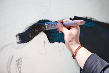 Kadın sanatçı, açık hava resim festivalinde beyaz tuvale boya fırçası sürrealist kız portresi çiziyor, resim çiziyor. Siyah şapkalı kadın atmosferik gerçeküstü resim çiziyor.