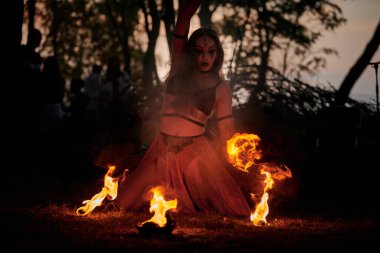 Açık hava sanat festivalinde kız ateş dansı gösterisi, akvaryumlu kadın ateş gösterisi sanatçılarının düzgün hareketleri. Alevli dans eden kadın sanat performansı, alacakaranlık ormanı arka planı