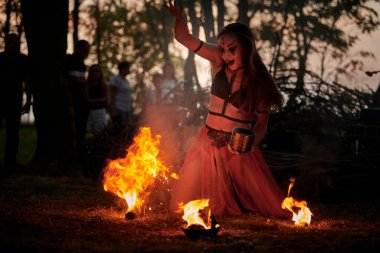 Açık hava sanat festivalinde kız ateş dansı gösterisi, akvaryumlu kadın ateş gösterisi sanatçılarının düzgün hareketleri. Alevli dans eden kadın sanat performansı, alacakaranlık ormanı arka planı