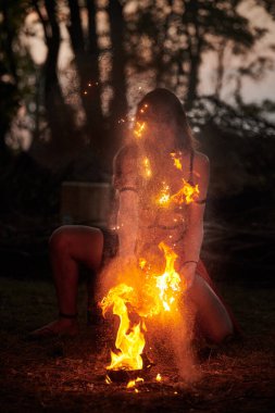 Açık hava sanat festivalinde kız ateş dansı gösterisi, dans eden kadın sanatçının ateş alevi gibi yumuşak hareketleri. Ateş sanatıyla dans eden kadın, alacakaranlık ormanı geçmişi