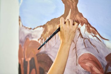 Ressam kız elinde boya fırçası ve açık hava resim festivalinde beyaz tuval üzerine soyut gerçeküstü manzara çiziyor, resim resim süreci. Kadın sanatçı atmosferik gerçeküstü resim çiziyor.