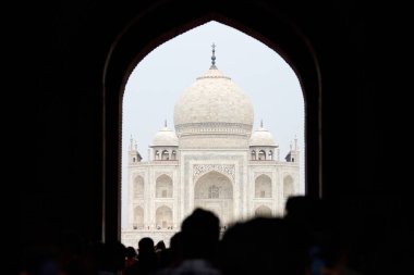 Tac Mahal girişinin ana giriş kapısı turist siluetleriyle, Taj Mahal mermer mozolesine bakın kemer, Hindistan 'da muazzam turist akını, Taj Mahal turizm sezonu
