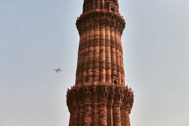 Kutub Minar minaresi, gökyüzü arka planında uçak, güney Delhi, Hindistan 'da kutup bölgesi, büyük kırmızı kumtaşı minare kulesi, Yeni Delhi' de popüler turistik bölge, en uzun tuğla minare.