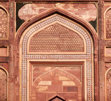 Tac Mahal 'in antik duvar dekoratif unsurları, geometrik desenleri tasvir eden güzel antik duvar süslemeleri, Taj Mahal' deki el yapımı eski kırmızı kum taşı süslemeleri.