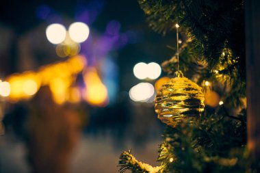 Noel ağacı süslemeleri karla kaplıydı, açık hava xmas ağacı dekoratif sarı ampuller, açık havada kış tatili atmosferi. Parlak sarı topları olan Noel ağacı.