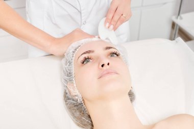 Gua Sha Taşı ile yüz masajı yapan kozmetik uzmanı, güzellik salonundaki lenfatik drenaj, yaşlanmayı önleyen estetik ameliyat için cilde bakıyor. Gua Sha aracıyla yüz masajı