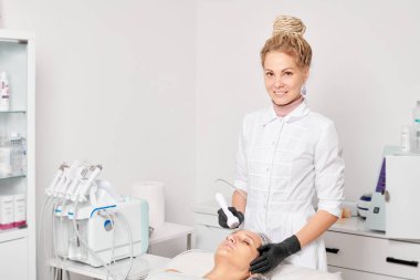 Güzellik uzmanı, güzellik salonundaki gençleştirme kadın yüzü için RF kaldırma, yaşlanma karşıtı kozmetik işlemleri yapıyor. Kozmetik uzmanı, kadın yüz derisinde artan kolajen için radyo frekansı tedavisi yapıyor.