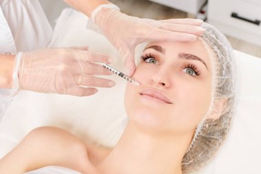 Kozmetik uzmanı güzellik salonunda dudak büyütme ve hacim için estetik cerrahi olmayan ameliyatlar yapıyor. Eldiven uzmanları şırınga ile iğne yapıyor.