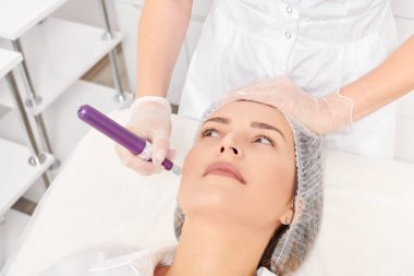 Kozmetik uzmanı, yenilenen kadın yüzü için mezoterapi enjeksiyonu yapıyor. Güzellik salonunda yaşlanmayı önleyen estetik cerrahi müdahale yok. Eldivenli güzellik uzmanı yüz mikro iğnesi yapar.