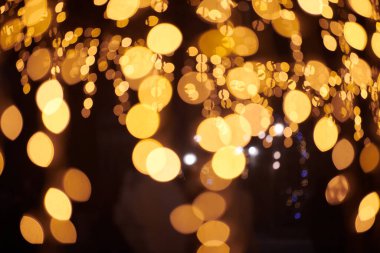 Sarı ışıklar Noel tatili çelenkleri, bulanık arka plan, soyut açık hava ışıkları ve sigara. Parlak sarı Bokeh ışıkları, güzel, karanlık gece arkaplanı.