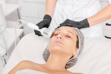 Güzellik uzmanı, gençleşen kadın yüzü için kriyoterapi yapıyor güzellik salonlarında yaşlanma karşıtı kozmetik prosedürler uyguluyor. Kozmetik uzmanı, cilt gençleştirme ve düzleştirme için kriyo terapi yapıyor.