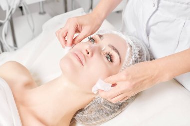 Kozmetikçiler güzellik salonundaki yüz kremi maskesini kadın yüzünden kozmetik mendillerle temizliyor, cilt yenileme estetik ameliyatları yapıyor. Güzellik uzmanları yüz maskesini çıkarmak için peçete tutuyor.