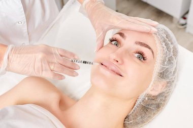 Kozmetik uzmanı güzellik salonunda dudak büyütme ve hacim için estetik cerrahi olmayan ameliyatlar yapıyor. Eldiven uzmanları şırınga ile iğne yapıyor.