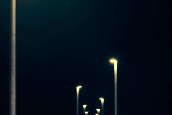 模糊的黄灯线从夜间灯柱 抽象的黄灯装饰城市的蓝色绿色夜晚天空背景 模糊的黄色交替的街灯 — 图库照片