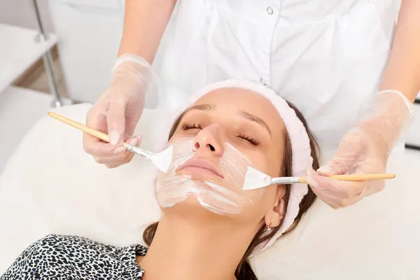 Beautician Applicera Kosmetisk Kräm Mask Kvinnans Ansikte För Föryngring Ansikte — Stockfoto