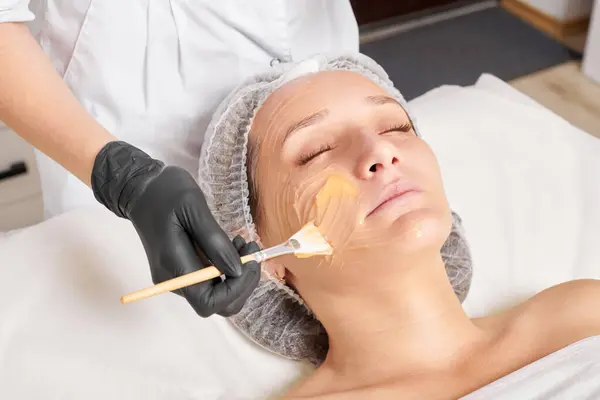 Kosmetikerin Trägt Honigmaske Auf Das Gesicht Der Frau Auf Die — Stockfoto