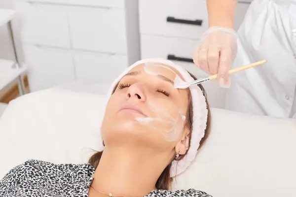 Kosmetolog Stosujący Kosmetyczną Maskę Kremową Kobiecej Twarzy Odmładzania Skóry Twarzy — Zdjęcie stockowe