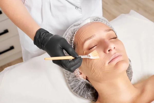 Kosmetikerin Trägt Honigmaske Auf Das Gesicht Der Frau Auf Die — Stockfoto