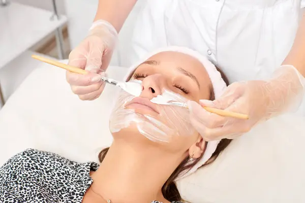 Kosmetolog Tillämpa Kosmetisk Kräm Mask Kvinnans Ansikte För Föryngring Ansikte — Stockfoto