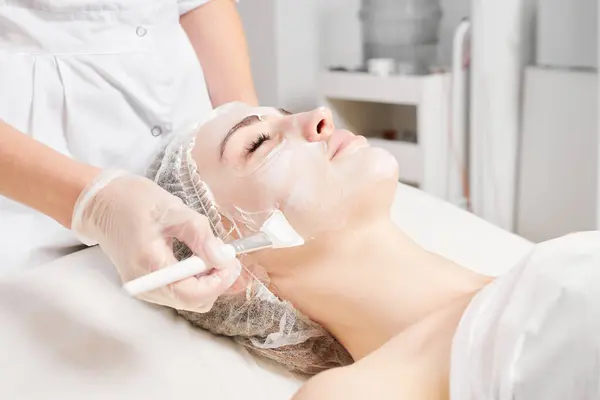 Kosmetolog Applicerar Kräm Mask Kvinnans Ansikte För Föryngring Ansikte Hud — Stockfoto