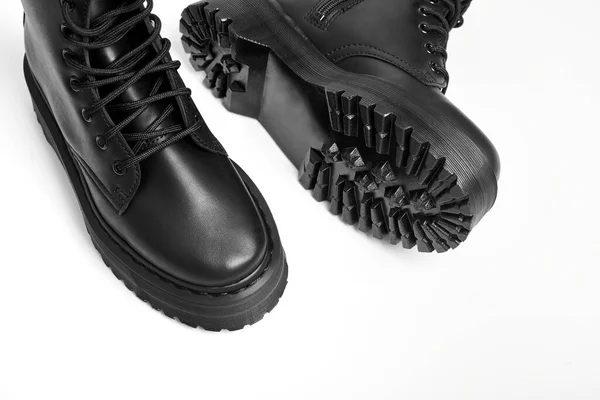 Black women combat boots on high heel platform with lug soles on isolated white background, close up. Military stylish high heel platform combat boots for woman legs, new footwear trends