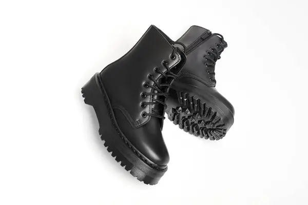 Black women combat boots on high heel platform with lug soles lying on isolated white background. Military stylish high heel platform combat boots for woman legs, new footwear trends