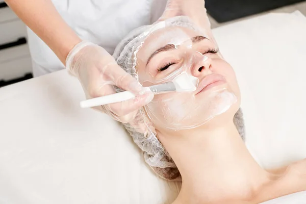 Kosmetolog Applicerar Kräm Mask Kvinnans Ansikte För Föryngring Ansikte Hud Royaltyfria Stockbilder