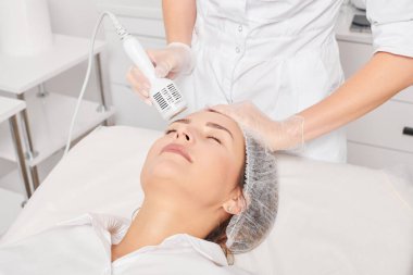 Beautician makes cryotherapy for rejuvenation woman face, anti aging cosmetic procedure with in beauty spa salon. Cosmetologist makes cryo therapy lifting with for skin rejuvenation and smoothing clipart