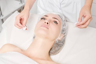 Kozmetikçiler güzellik salonundaki yüz kremi maskesini kadın yüzünden kozmetik mendillerle temizliyor, cilt yenileme estetik ameliyatları yapıyor. Güzellik uzmanları yüz maskesini çıkarmak için peçete tutuyor.