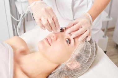 Kozmetik uzmanı kadın yüzüne gençleştirme enjeksiyonu yapıyor. Güzellik salonunda yaşlanmayı önleyen estetik cerrahi olmayan prosedür uyguluyor. Eldiven uzmanları şırınga ile iğne yapıyor.