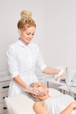 Kozmetik uzmanı yüz gazı sıvısı oksijen serumu epidermal kabuğunu gençleştirme için cilt bakımı, güzellik salonundaki yaşlanma karşıtı kozmetik prosedürü yapıyor. Güzellik uzmanı yüz bakımı yapıyor