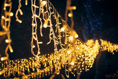 Sarı ışıklar Noel tatili çelenkleri, bulanık arka plan, soyut açık hava ışıkları ve sigara. Parlak sarı Bokeh ışıkları, güzel, karanlık gece arkaplanı.