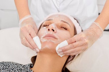 Kozmetikçiler güzellik salonundaki yüz kremi maskesini kadın yüzünden kozmetik mendillerle temizliyor, cilt yenileme estetik ameliyatları yapıyor. Güzellik uzmanı nemlendirici kremi peçeteyle kaldırıyor.