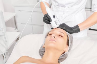 Güzellik uzmanı, gençleşen kadın yüzü için kriyoterapi yapıyor güzellik salonlarında yaşlanma karşıtı kozmetik prosedürler uyguluyor. Kozmetik uzmanı, cilt gençleştirme ve düzleştirme için kriyo terapi yapıyor.