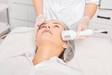 Kozmetik uzmanı gençleşen kadın yüzü için kriyoterapi yapıyor, güzellik salonundaki yaşlanma önleyici kozmetik prosedürler. Güzellik uzmanı, cilt gençleştirme ve yumuşatmak için kriyo terapi yapıyor.